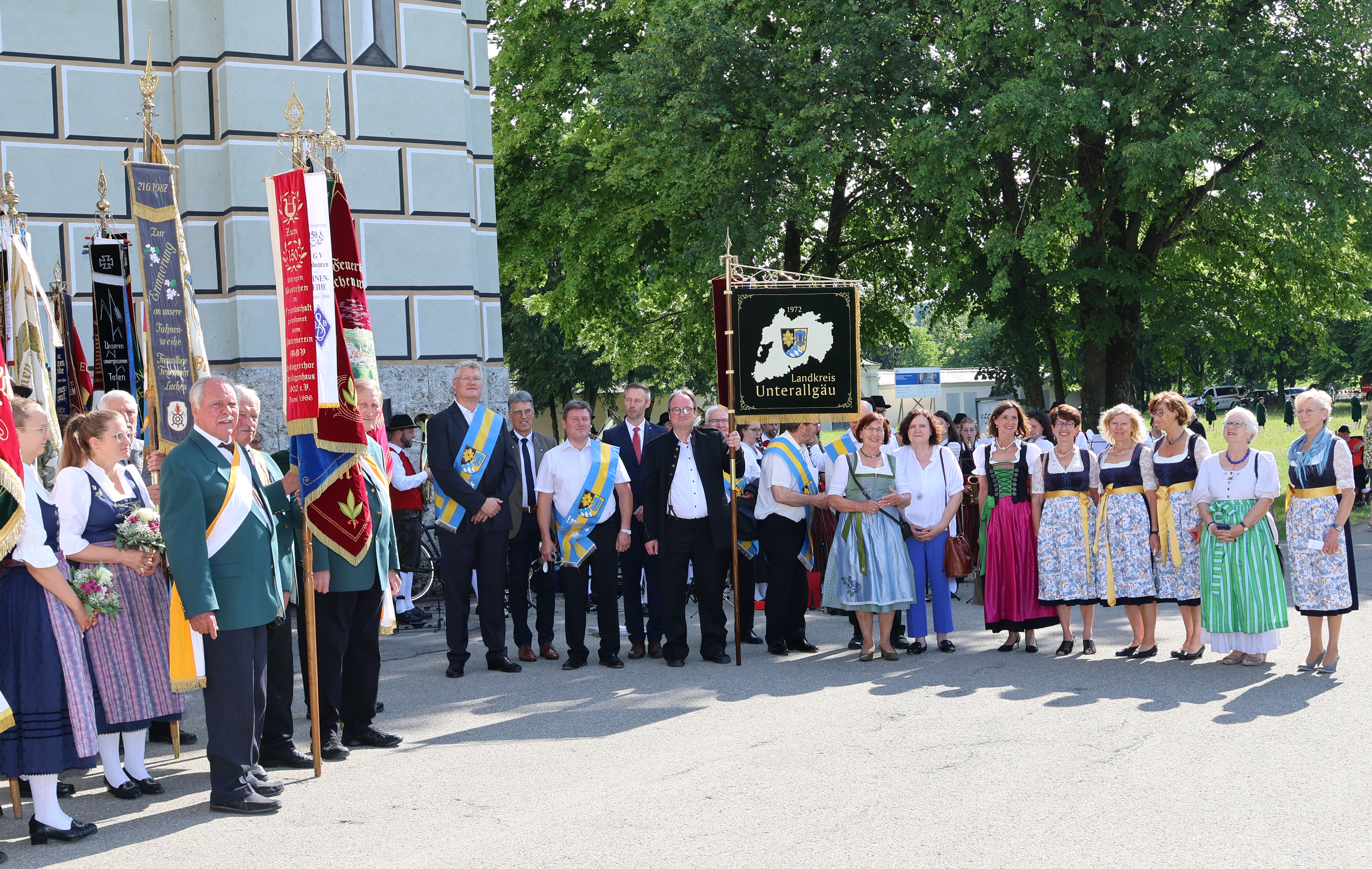 Fahnenträger und viele weitere Gästen stehen vor der Basilika Ottobeuren, als der Fähnrich die Landkreis-Standarte präsentiert. 