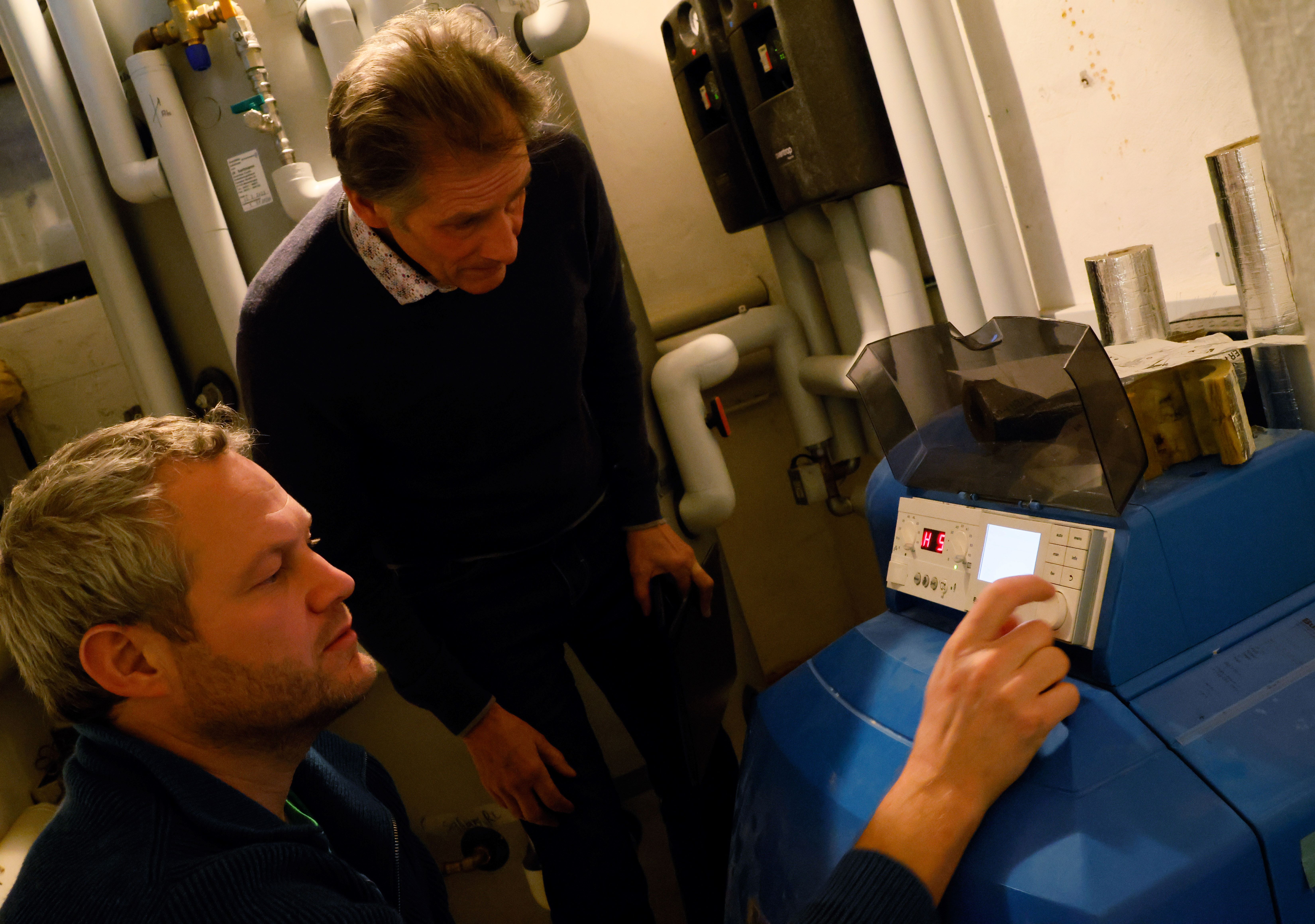 Das Bild zeigt Energieberater Peter Andreas-Tschiesche und Christoph Markert aus Wolfertschwenden im Heizungskeller. Die Beiden betrachten das Digitaldisplay einer Heizung