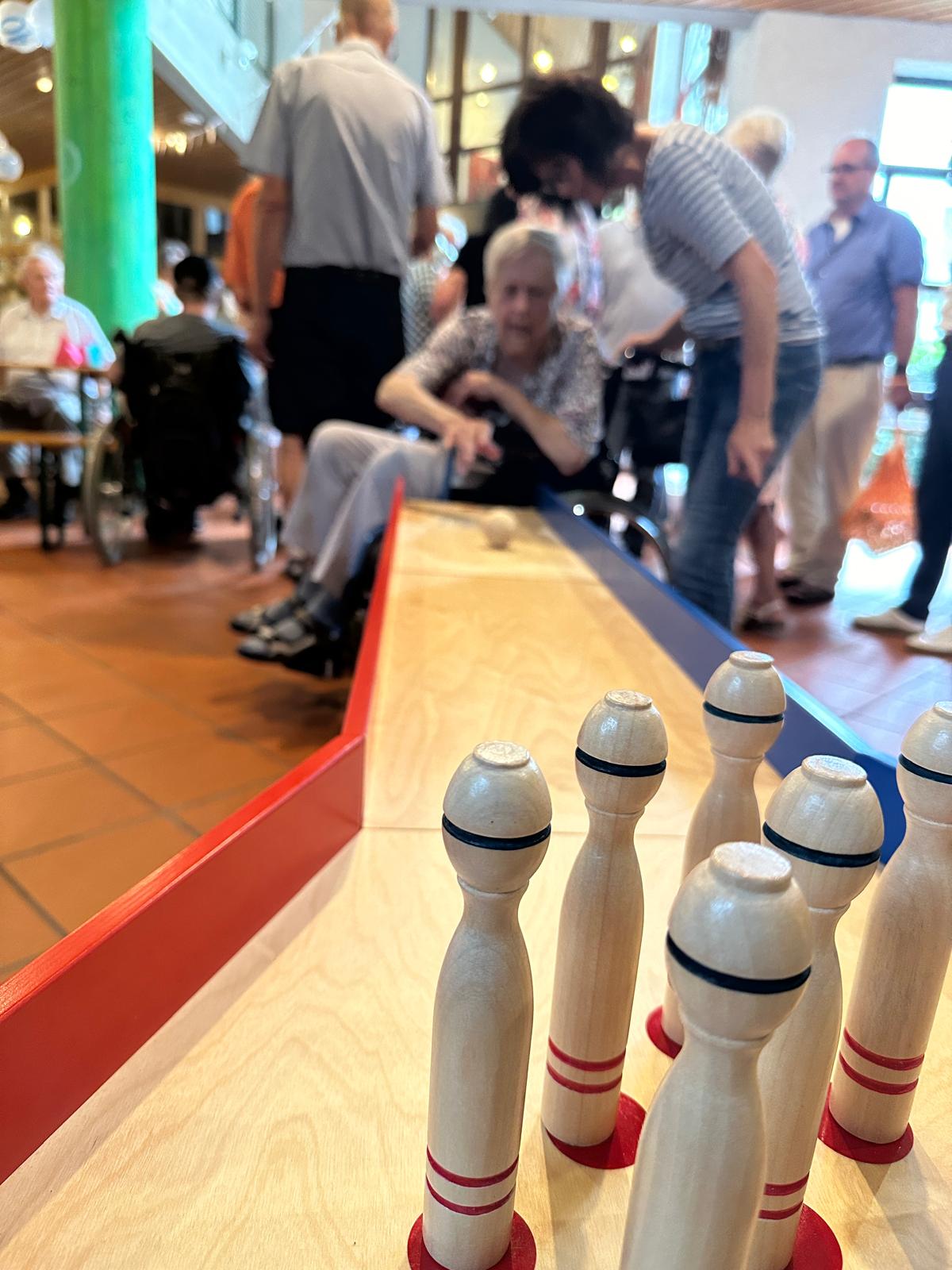 Eine Seniorin im Rollstuhl an der Tischkegelbahn. 