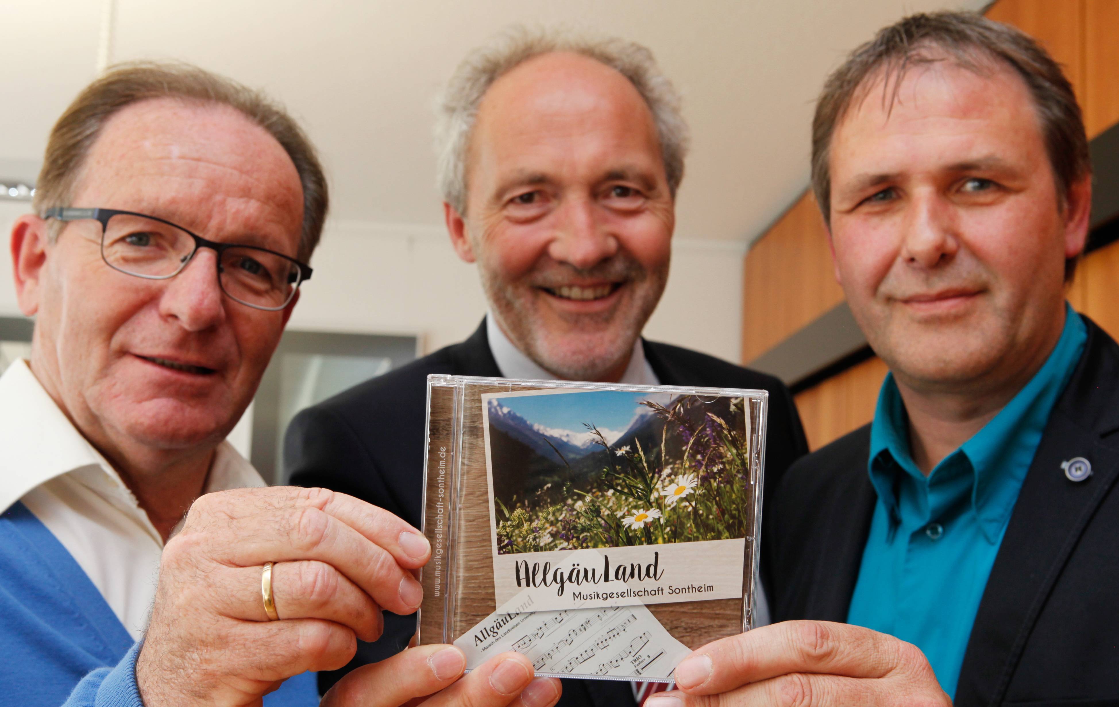 Der Unterallgäu-Marsch „AllgäuLand“ ist auf der gleichnamigen CD der Musikgesellschaft Sontheim zu hören, die Dirigent Berthold Leicht (links) und Vorsitzender Roland Diem (rechts) an Landrat Weirather übergeben haben. Foto: Vögele/Landratsamt