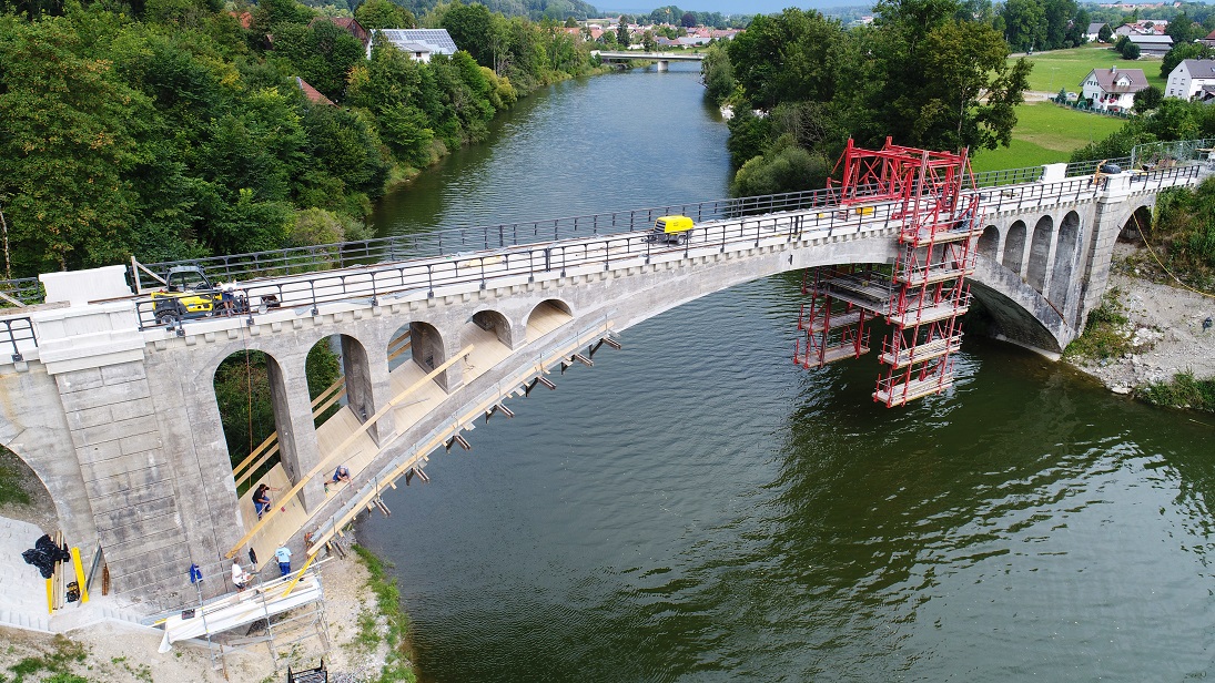 Vieles über die alte Eisenbahnbrücke über die Iller zwischen Lautrach und Illerbeuren kann man beim „Tag des offenen Denkmals“ am 9. September erfahren. Der linke Teil des Bogens (bis zum Hängegerüst) ist bereits saniert, rechts im Bild ist noch der alte Zustand zu sehen. Im Hintergrund sieht man die Illerbrücke, die der Landkreis im Jahr 2010 neu gebaut hat. Foto: Stefanie Vögele/Landratsamt Unterallgäu